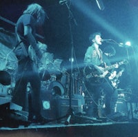 a group of people on stage with guitars and drums