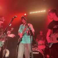 a group of young men playing guitars on stage